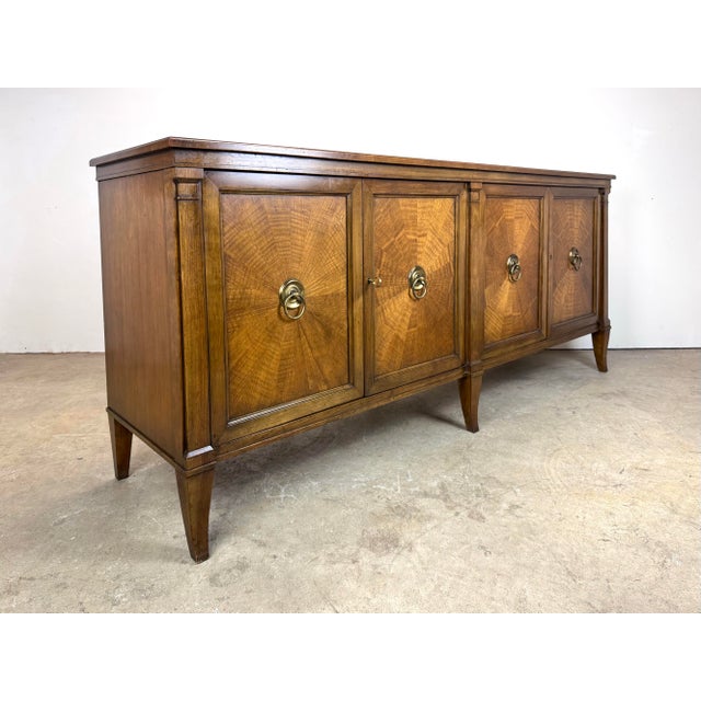 A fine Baker Furniture French Regency style sideboard in walnut with beautiful radial door veneer, heavy brass pulls and...