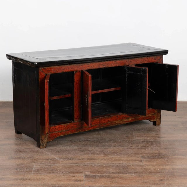 The red lacquered polished finish with contrasting black top on this small Chinese sideboard provides a modern look...