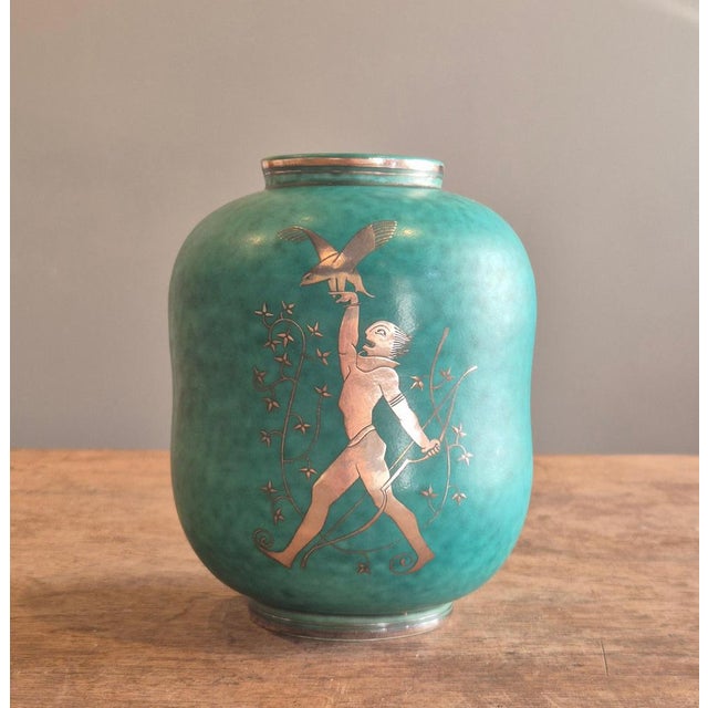 A Swedish modern classic, stoneware vase in signature green glaze with decor of a mythical figure/huntsman with falcon,...