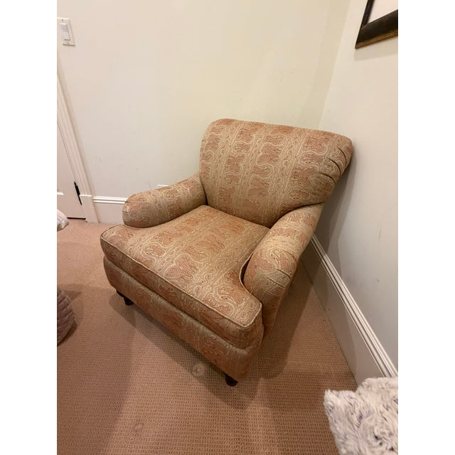 This elegant custom upholstered armchair features a classic rolled‑arm silhouette paired with a richly patterned neutral...