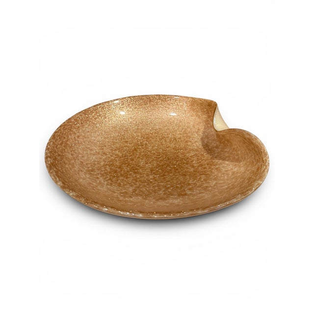 A large Murano glass dish in a warm gold-copper tone, featuring shimmering aventurine flecks throughout. The piece has an...