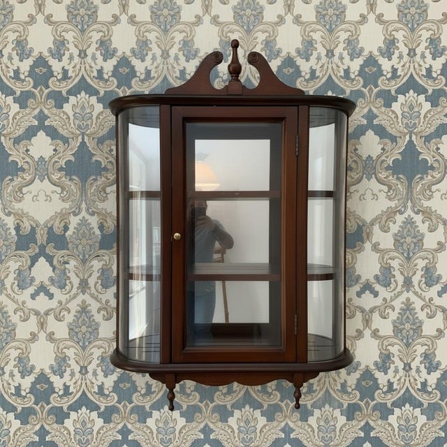 This is a handsome wall-mounted curved glass display cabinet or hanging vitrine to showcase collectibles, figurines, small...