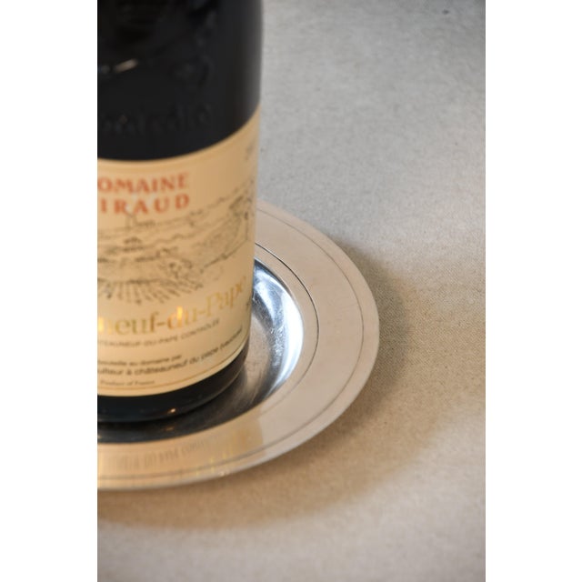 An elegant French silver-plated bottle coaster by Christofle, featuring a classic circular silhouette with a broad, subtly...