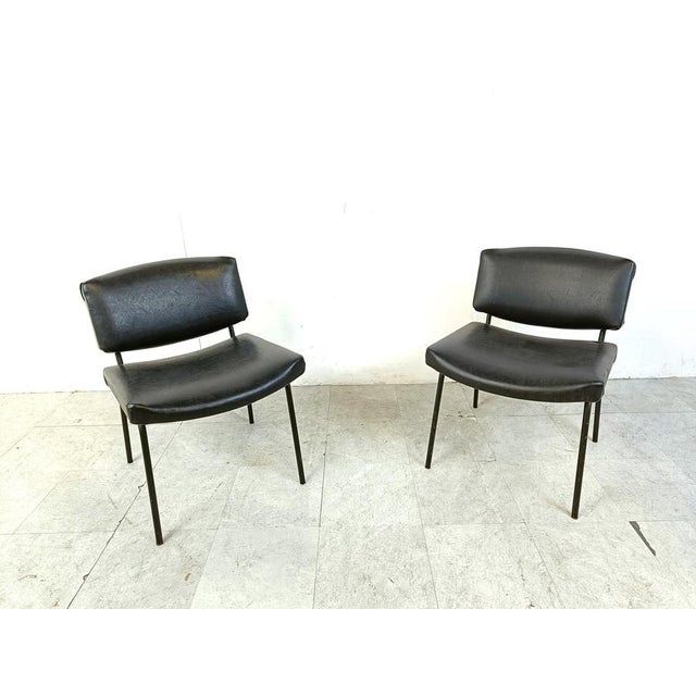 Set of 2 mid century modern 'conseil' chairs designed by Pierre Guariche for Meurop. The chairs have a black lacquered...