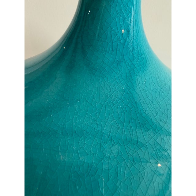 This glazed table lamp has a vibrant turquoise ceramic base with a crackle finish. The drum shade is in a creamy linen....