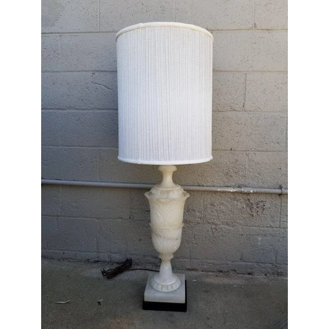 Monumental carved alabaster table lamp mounted to ebonized wood base. Alabaster urn measures 25"H. Overall height 47" to...