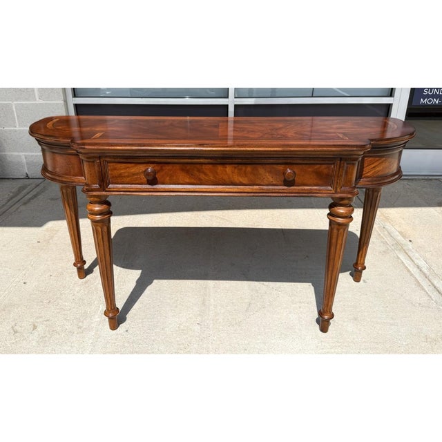 This elegant foyer table features a richly figured wood top accented with decorative banding and gracefully rounded ends...