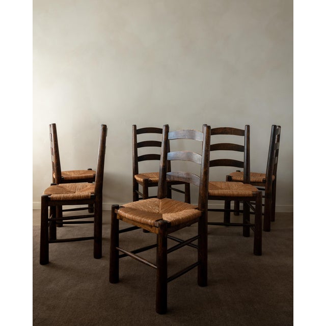 A vintage French dining chair set in dark stained wood and woven rush, attributed to Georges Robert and produced in France...