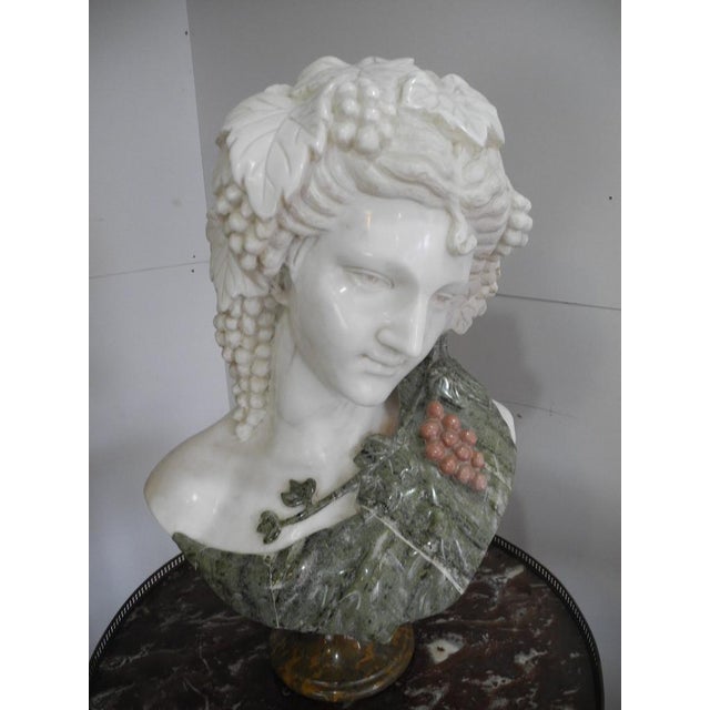 Antique, highly exclusive Carrara marble bust of a woman with a laurel wreath and grapes in her hair. The bust is crafted...
