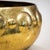 Large circular brass planter featuring a polished and hammered surface. The rim is decorated with repoussé half-sphere...