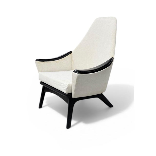 A mid-century modern sculptural high-back lounge chair with sweeping black walnut arms and base. Designed by Adrian...