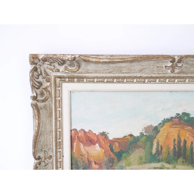 A colourful rock mountain landscape painting on a canvas board in oil. Small french village church with trees and on a...