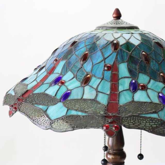 A Tiffany-style table lamp, crafted in the 20th century, features a dome-shaped shade composed of numerous pieces of...