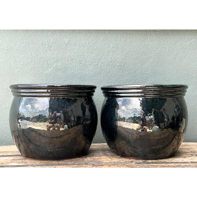 This striking pair of vintage ceramic planters showcases an exceptional "black over green" glaze, where deep ebony tones...