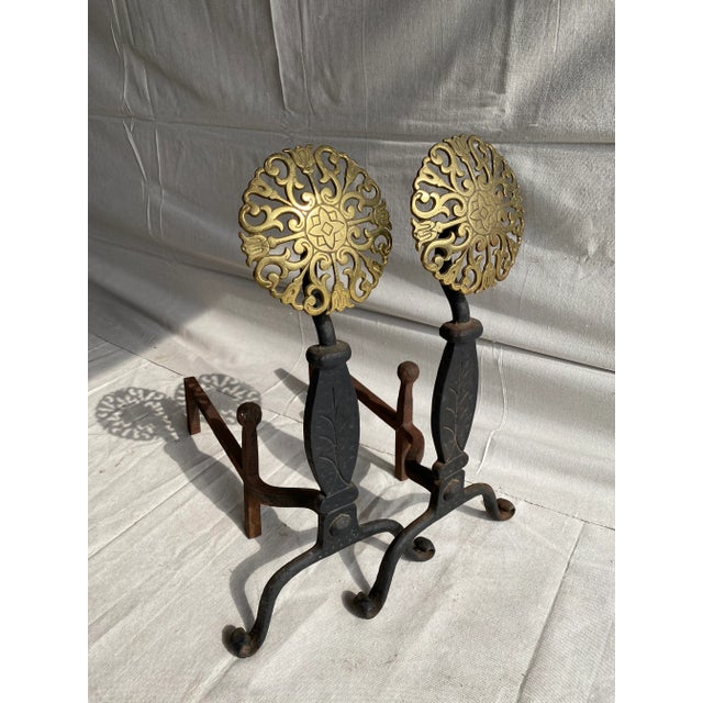 A nice pair of large aged forged iron and brass andirons thought to be from the early to mid 20th century. Surmounted by...