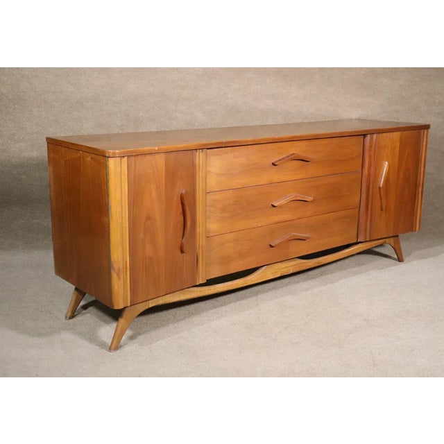Long American walnut dresser with nine drawers. Features organic boomerang handles and matching sculpted base. Please...