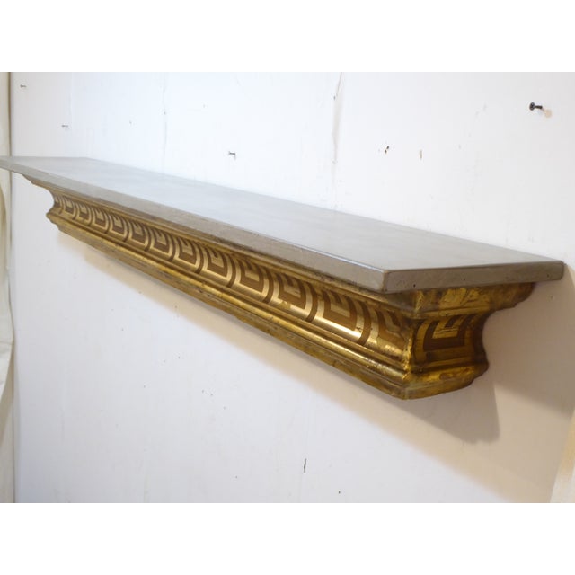This shelf, made with a 19th Century giltwood architectural fragment, has a wooden hanging mechanism for easy installation.