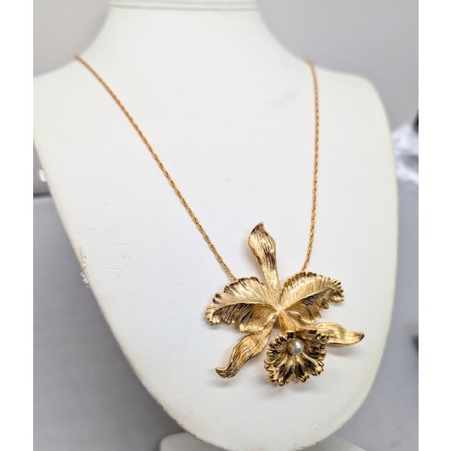 1964 goldtone orchid with faux-pearl center pendant necklace on a thin chain with spring ring clasp. Marked "NAPIER©" on...