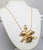 1964 goldtone orchid with faux-pearl center pendant necklace on a thin chain with spring ring clasp. Marked "NAPIER©" on...