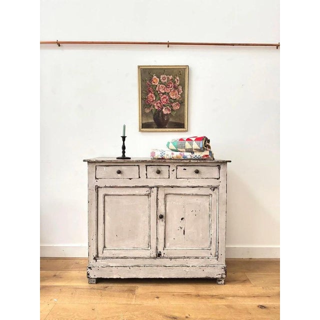 A lovely chippy painted wooden cupboard with a distressed grey finish, featuring three small top drawers and shelved...