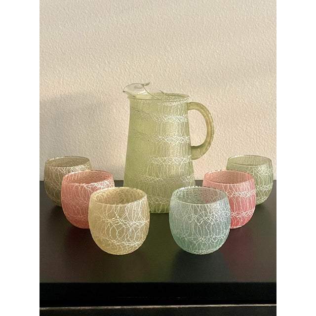 A Colorful Mid-Century Modern 1960s "spaghetti string" pitcher and 6 roly-poly glasses set by Color Craft. The glassware...