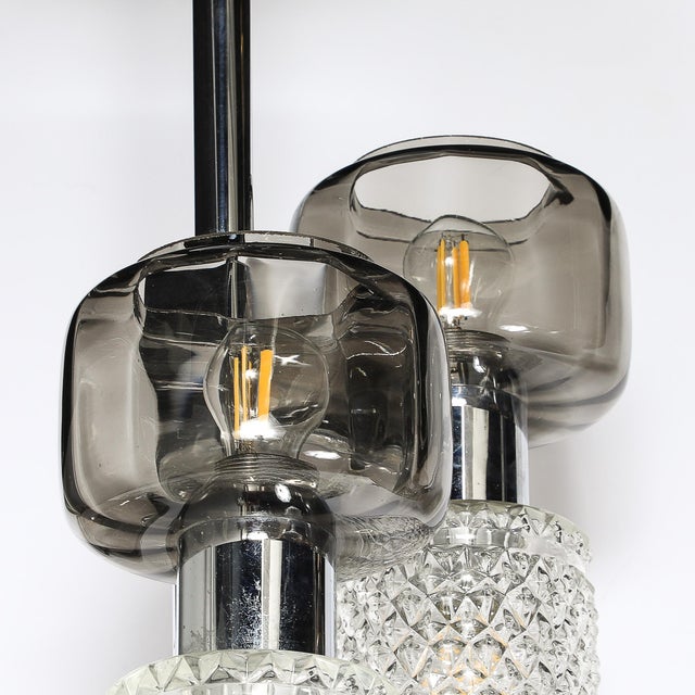 This mid-century modernist staggered three-arm pendant chandelier, crafted in Italy circa 1970, is a refined example of...