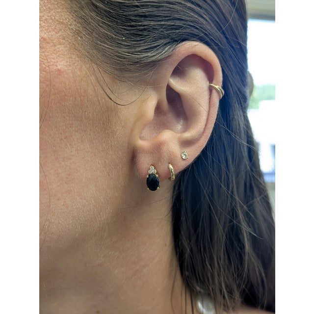 These elegant oval black spinel studs, mined from Madagascar, are set in solid 14K yellow gold and accented with natural...