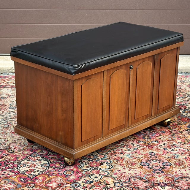 This stylish mid-century walnut storage bench features a vintage wood finish, vinyl top with interior record storage, and...