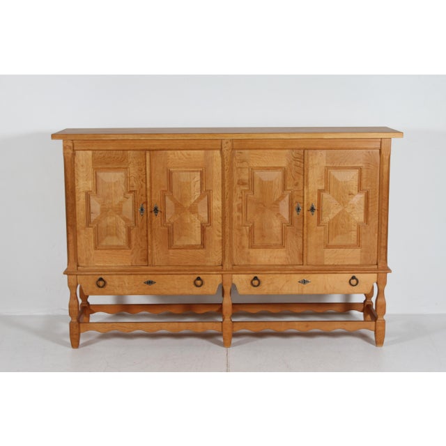 High sideboard by the danish designer Henning Kjærnulf. The country and brutalist style sideboard is made of solid and...