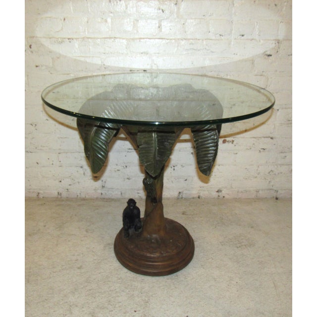 This incredibly sculpted side table evokes tropical themes with its palm tree base. A small monkey is seated at the base...