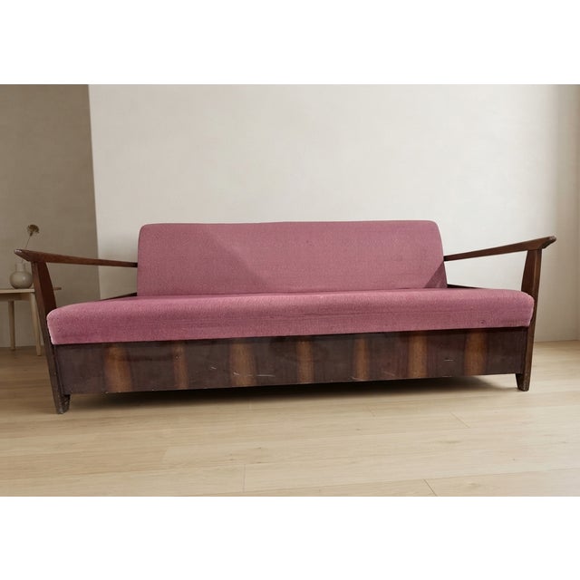 A stylish folding sofa bed designed by Edmund Homa, featuring a solid wooden frame with clean architectural lines and...