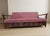 A stylish folding sofa bed designed by Edmund Homa, featuring a solid wooden frame with clean architectural lines and...