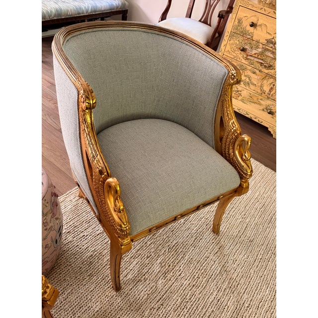 Gorgeous pair of gilt accent chairs with arms of carved swans. Recently reupholstered in Kravet pale blue performance...