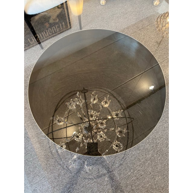 Elevate your dining space with this striking round dining table, featuring a clear glass top perched on a bold, polished...