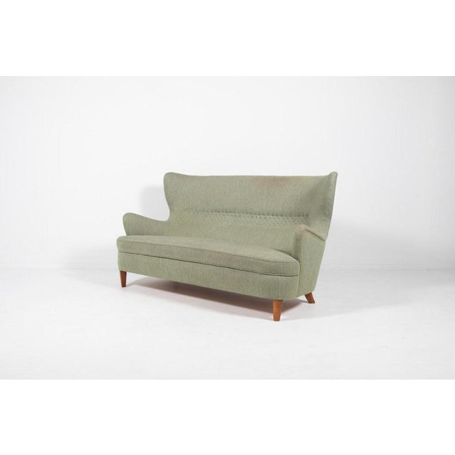 Very rare imposing wingback sofa from the pioneer of the Swedish modern movement Carl-Axel Acking. Stained wood legs with...