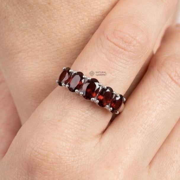 Graceful and timeless, this elegant multi-stone ring showcases a harmonious row of rich red gemstones, creating a refined...