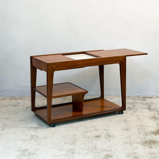 A drinks trolley by Remploy with a sliding top. Closed, it reads as a neat rectangle with a raised lip along the edges....