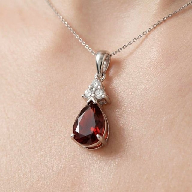 This exquisite pendant features a striking Garnet gemstone, celebrated for its deep, fiery red tones and timeless allure....