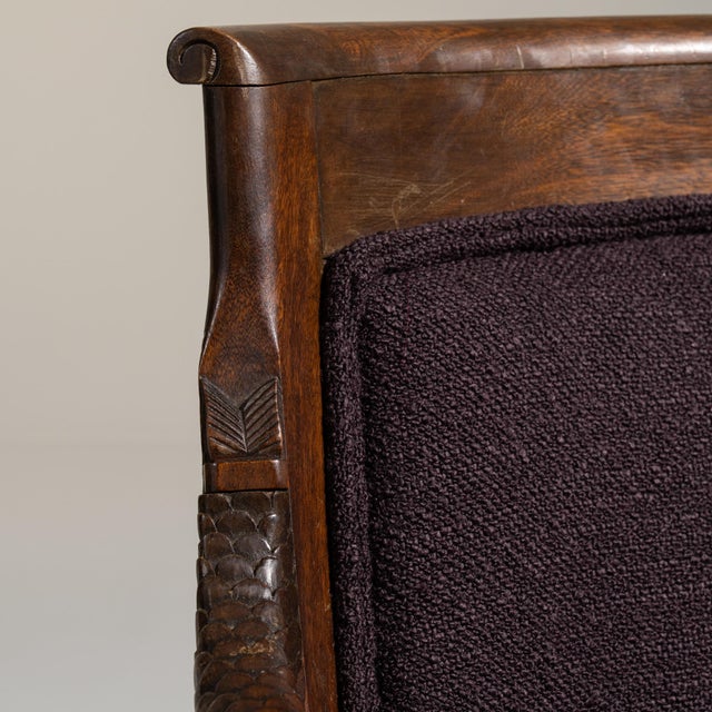 A red wood, Empire-style armchair, dating to the early 20th century and made in France. The wood frame is finished in...