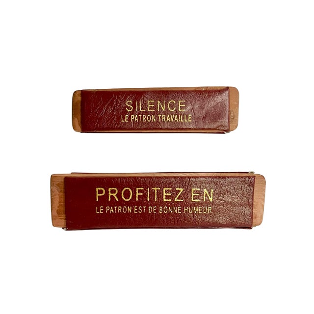 A distinctive pair of vintage French desk signs dating to the mid-20th century, featuring rich burgundy faux leather faces...