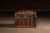 Domed top steamer trunk clad in embossed metal with repeating floral pattern, reinforced by vertical wood slats and...