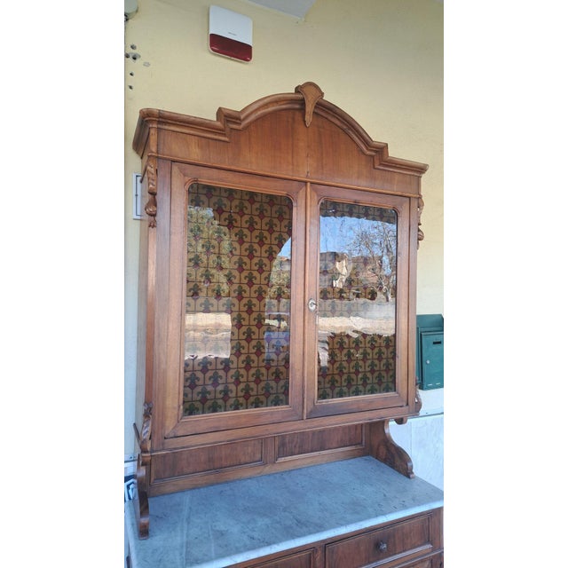 NINETEENTH CENTURY (1800 - 1900) Italian walnut display cabinet. Late 19th century. White Carrara marble top. The cabinet...