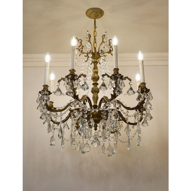 A 1940s neoclassical-style cut crystal chandelier, inspired by the Louis XVI style. The bronze structure features balanced...