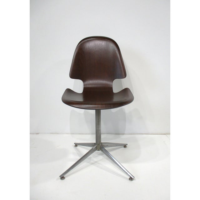 A sculptural molded dark walnut Hourglass swiveling desk chair with sturdy metal four star base and foot pads . A rare...