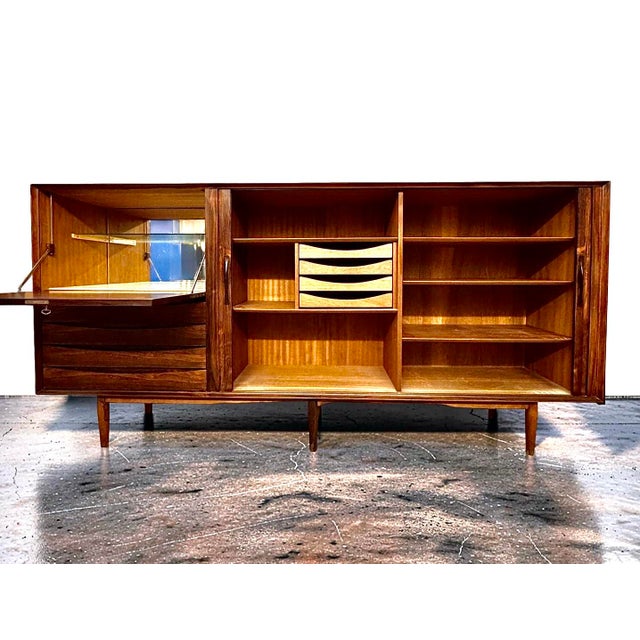 This exquisite mahogany highboard, designed by Arne Vodder and produced by Sibast Mobler, is a stunning example of mid-...