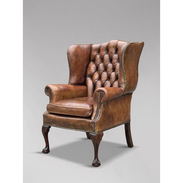 A high-quality, untouched 19th-century brown leather button back wing armchair in the George III style. The substantial,...