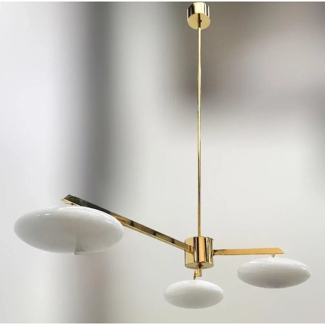 Italian pendant with three glossy white Murano glass shades mounted on solid brass frame in lacquered polished brass...
