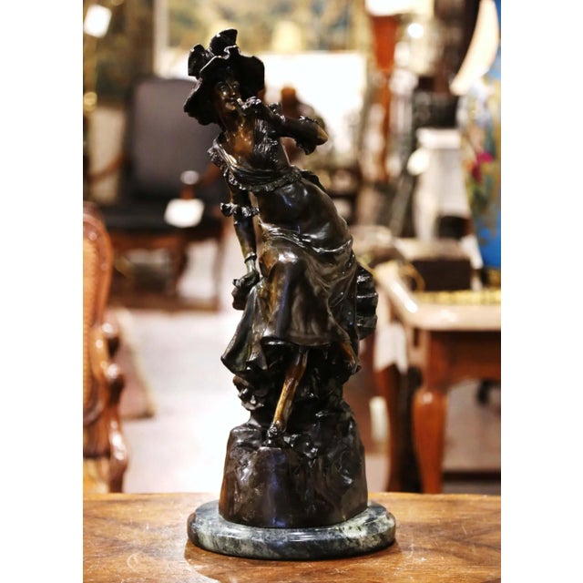 An elegant and highly decorative French bronze sculpture titled La Belle aux Jumelles, depicting a fashionable young woman...