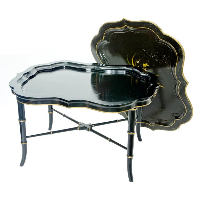 A 19th century ebonized paper mâché tray which fits into the elegant wood tray table. The paper mache tray has gilt edges...