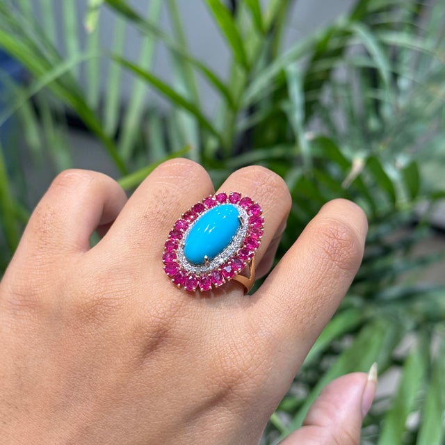 This handmade cocktail ring features a 9.1-carat oval cabochon turquoise and rubies, set in 14k yellow gold. The center...